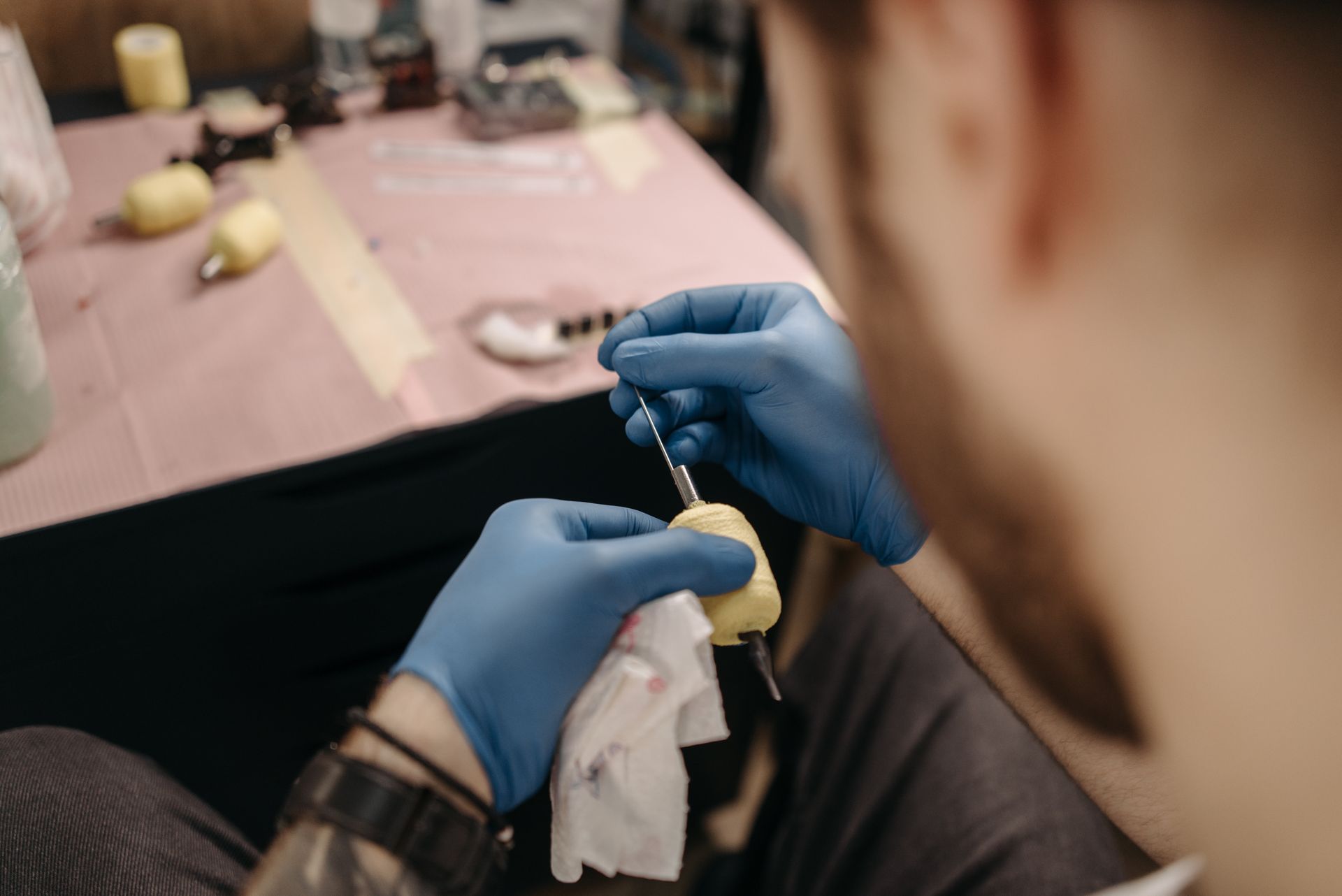 Tatuatore con guanti prepara la macchinetta con grip protetto